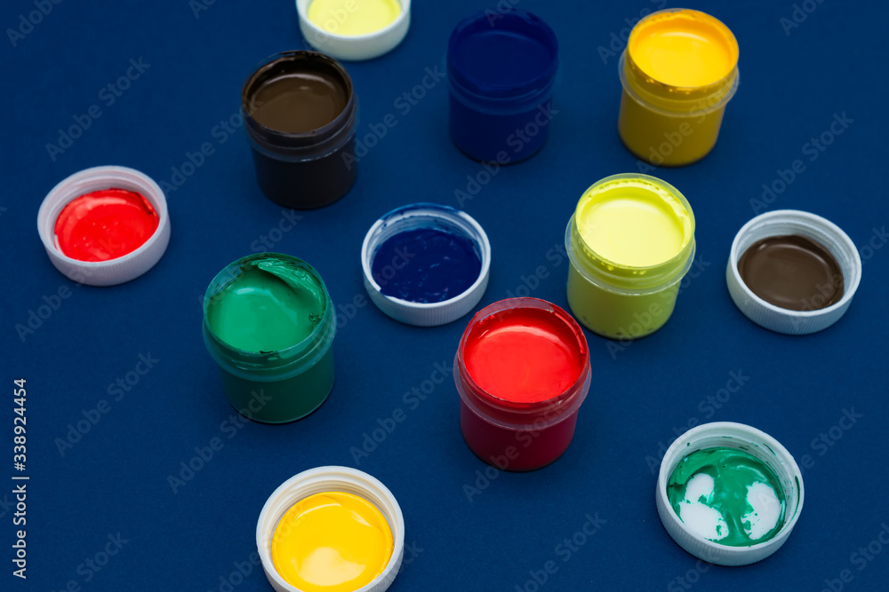 Close up of open acrylic paint cans. Colorful paints on blue background Close up of open acrylic paint cans. Colorful paints on blue background