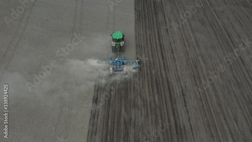 Top view of a spacious meadow getting scattered with seeds by a combine . Agriculture, tractor plow the earth in field, view from height.