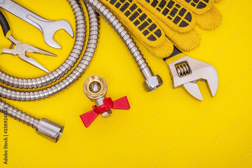 Plumbing tools and gloves for connecting water hoses on a yellow table for work Plumbing tools and gloves for connecting water hoses on a yellow table for work