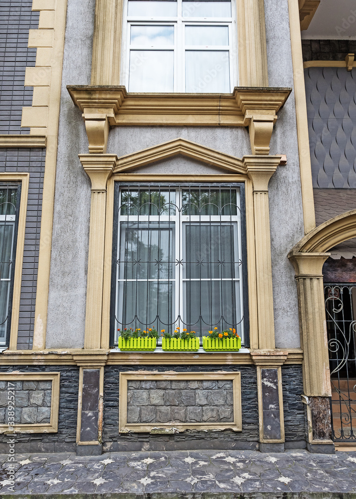 Window on the facade of the building with decor and flowers on the windowsill