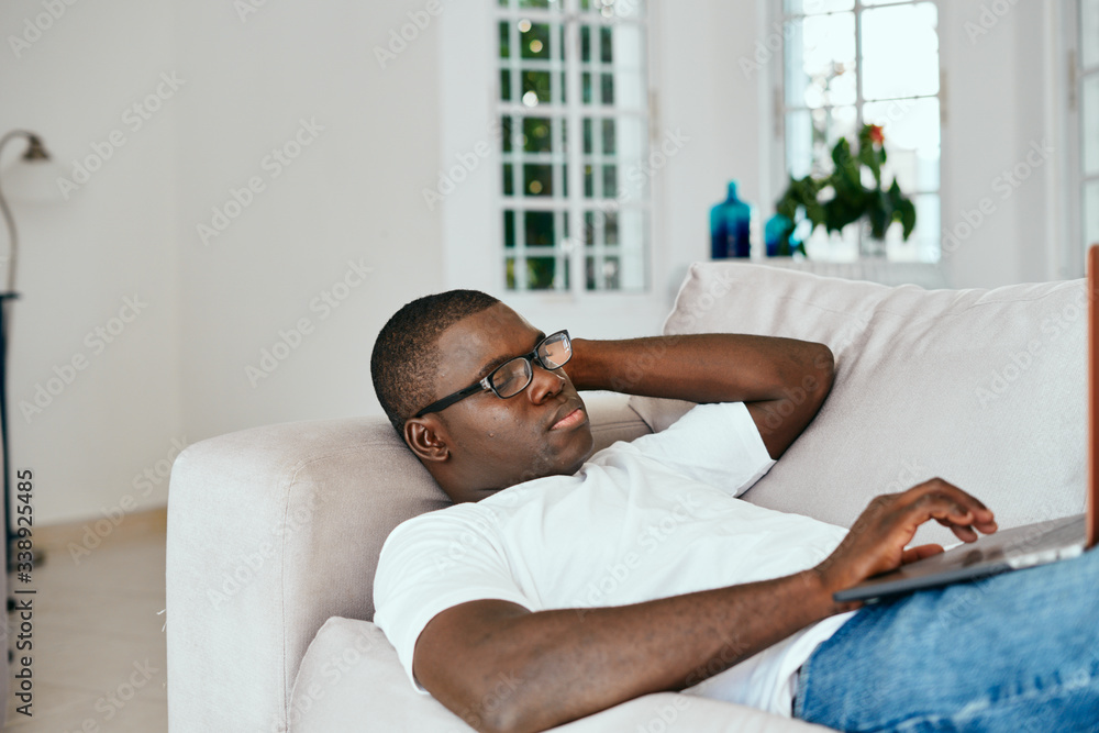 A man of African appearance at home in front of a laptop watching a movie A man of African appearance at home in front of a laptop watching a movie