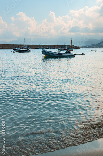 a fragment of a sandy beach with a moving sea wave with small motor boats parked in a quiet bay in the Greek resort of Hersonissos