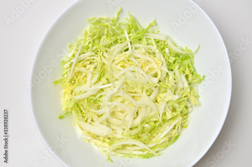 Fresh chinese cabbage salad in bowl on white table background. Vegan food lifestyle. Top view.