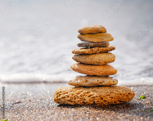 Stones pyramid on sand symbolizing zen, harmony, balance. Ocean in the background. Soft focus.