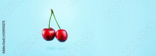 Falling red cherry over blue background, levitating berries, the concept of summer healthy food
