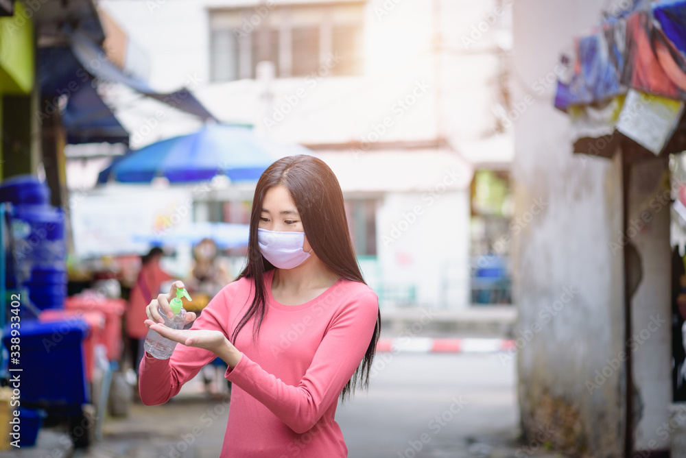 Asian woman wearing a mask to protect against air pollution and the corona virus ,woman washing hands with hand sanitizer to avoid contaminating with Coronavirus outbreak