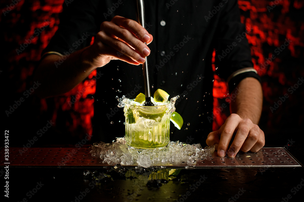 Obraz premium close-up barman in black t-shirt mix cocktail using metal madler