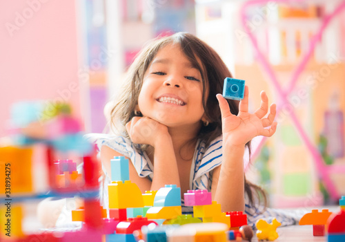 Photographie Little Girl Holding Construction Blocks in Hand at Home