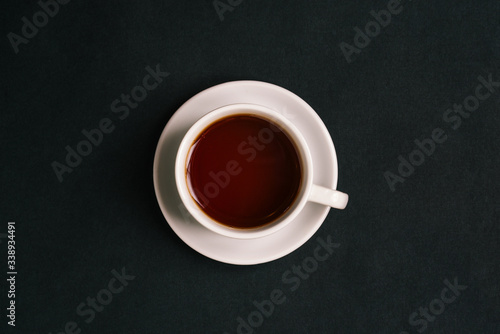 White cup with tea on a black background. Fragrant hot tea. Top view, flat lay.