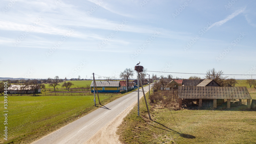 Aerial view of white storks nesting on electric pole in spring. Panoramic view of single stork in the nest on the classic blue sky background. Ornithological monitoring of the stork from above.
