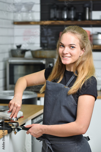 Young barista girl makes coffee and smiles. Small business and work concept for young people