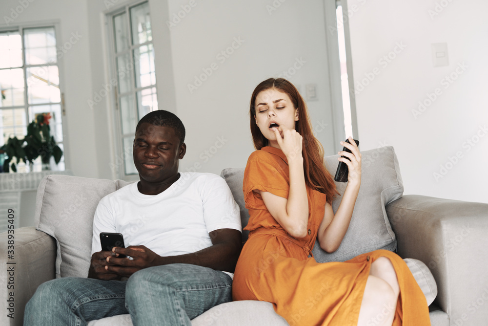 Obraz premium Young couple at home on the couch with a phone in their hands chatting