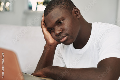 A man of African appearance at home in front of a laptop watching a movie