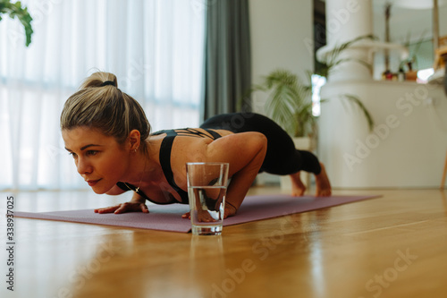 Close up photo of young woman in sportswear doing push-ups on mat at home. Young woman exercising at home in self quarantine due to COVID19 pandemic.