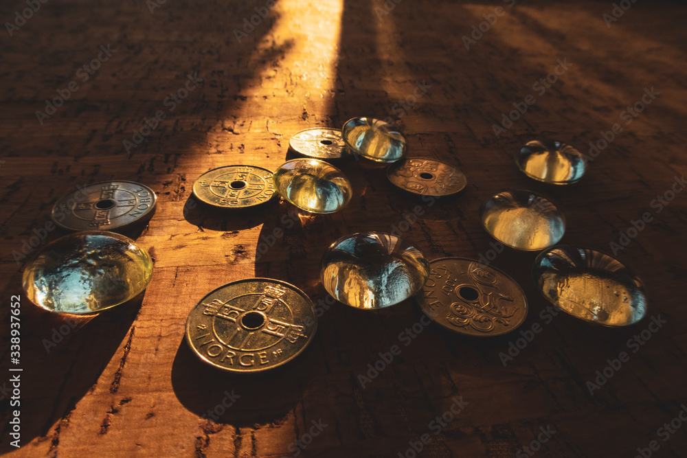 Closeup of a pile of Norwegian money on a cork background, illuminated by a beam of sunlight.