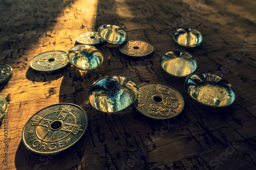Closeup of a pile of Norwegian money on a cork background, illuminated by a beam of sunlight.
