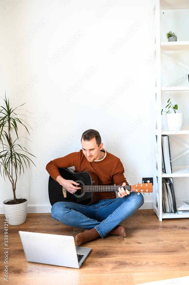 A guy watches video tutorial on guitar playing