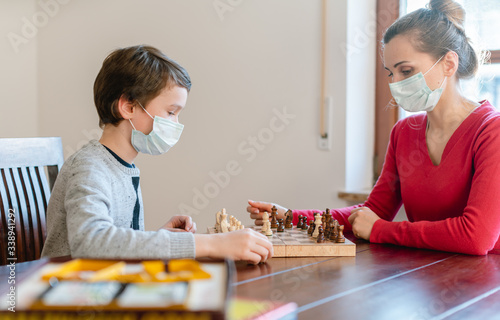 Mother and kid during coronavirus crisis playing chess at home