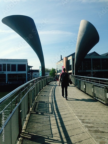 Fotografija Rear View Of Man Walking On Pero Bridge Against Sky