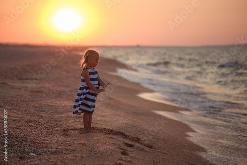 little girl child stands on the beach, sunset by the water summer, beach