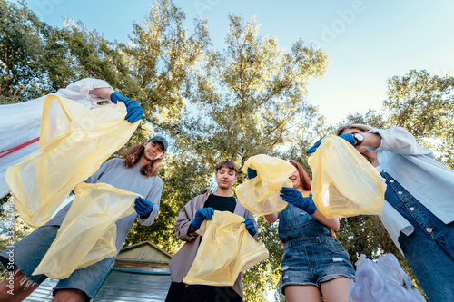 Group of activists friends throw a lot of garbage in a bag. Bottom-up shooting