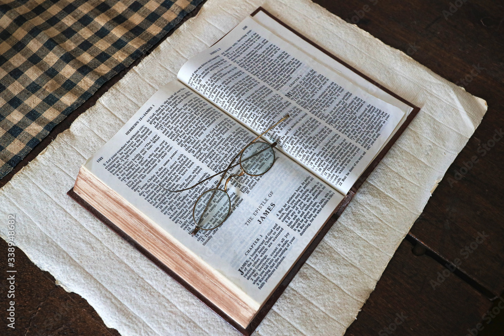 Obraz premium Bible pioneer reading glasses Book of James. Christian church receives Revelation to organize and worship God and Christ. Religion religious script and testimony of Christ.