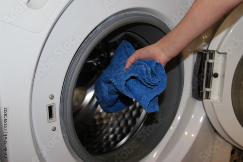 Woman hands loading towel into wahing machine. 