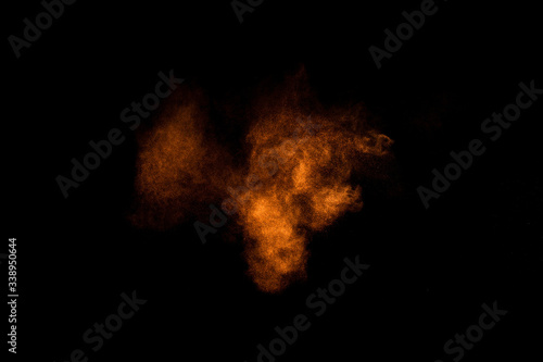 Orange powder explosion on black background. Colored powder cloud. Colorful dust explode. Paint Holi. © sergio34