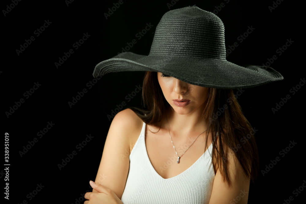 beautiful young woman in a black hat on a black background beautiful young woman in a black hat on a black background