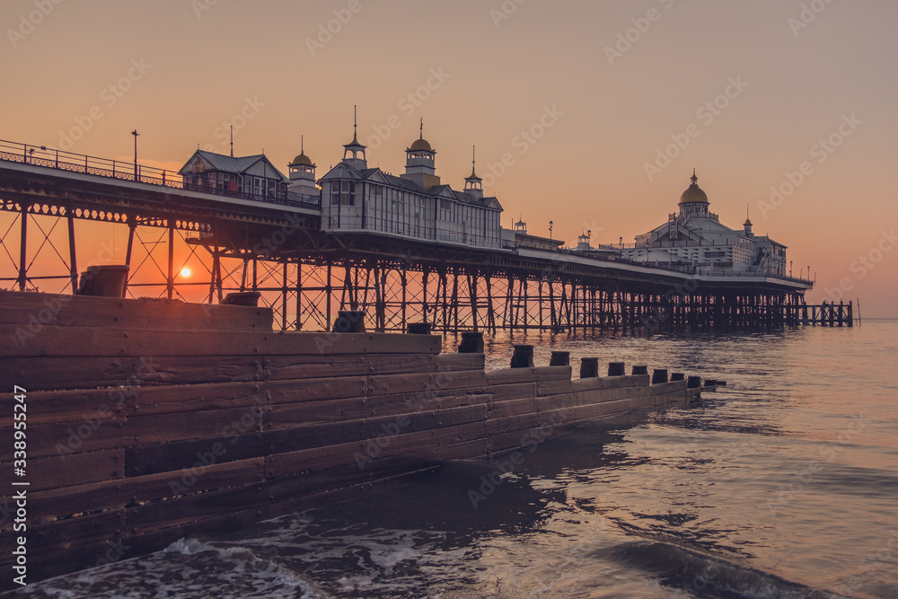 Fototapeta premium Eastbourne Pier at sunrise with a groyne in the foreground