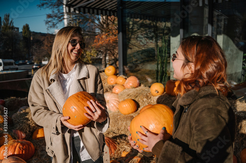 Girls holds pumpkins in hands. Outdoor photo.