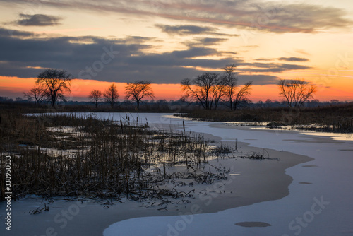 Vivid winter sunset colors over a frozen wetland conservation area.