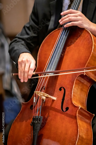 Man playing a cello using a bow in during a ceremony
