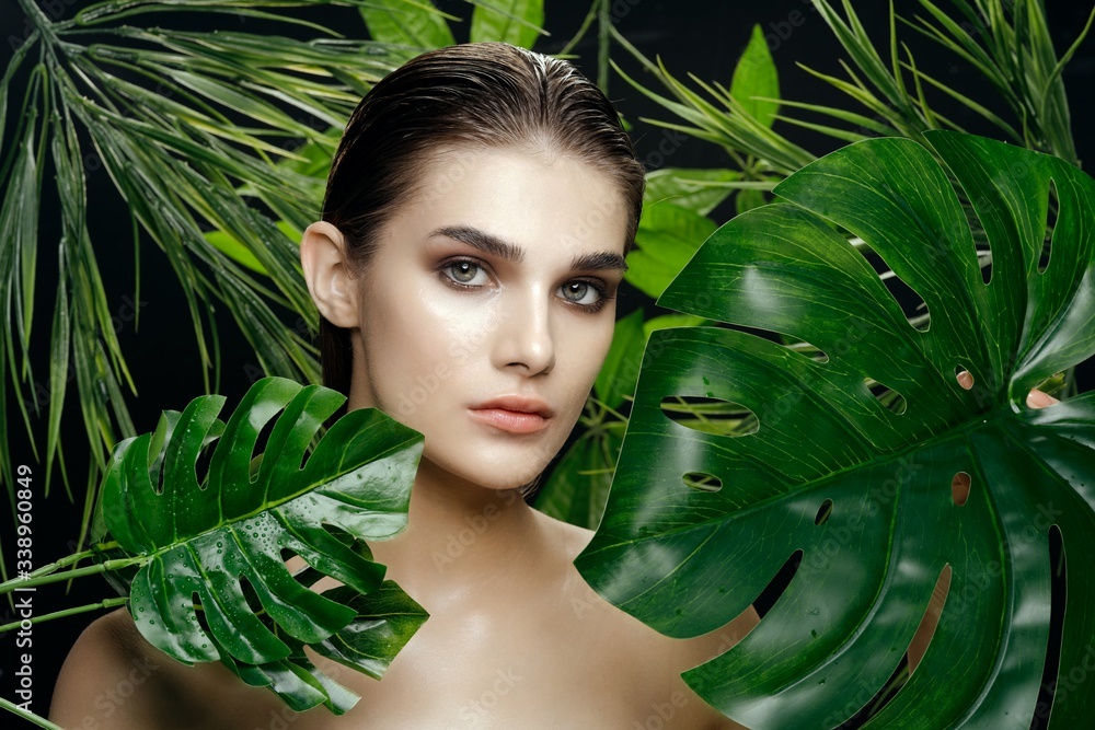 Beautiful woman and green leaves naked shoulders charm cosmetics jungle Beautiful woman and green leaves naked shoulders charm cosmetics jungle