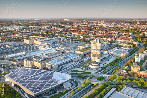 Modern European aerial cityscape with skyscraper, industrial, commercial and residential buildings and circle intersection of roads at sunset in outskirts of Munchen Bavaria Germany Europe