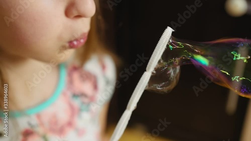 Small girl blowing bubbles at home.