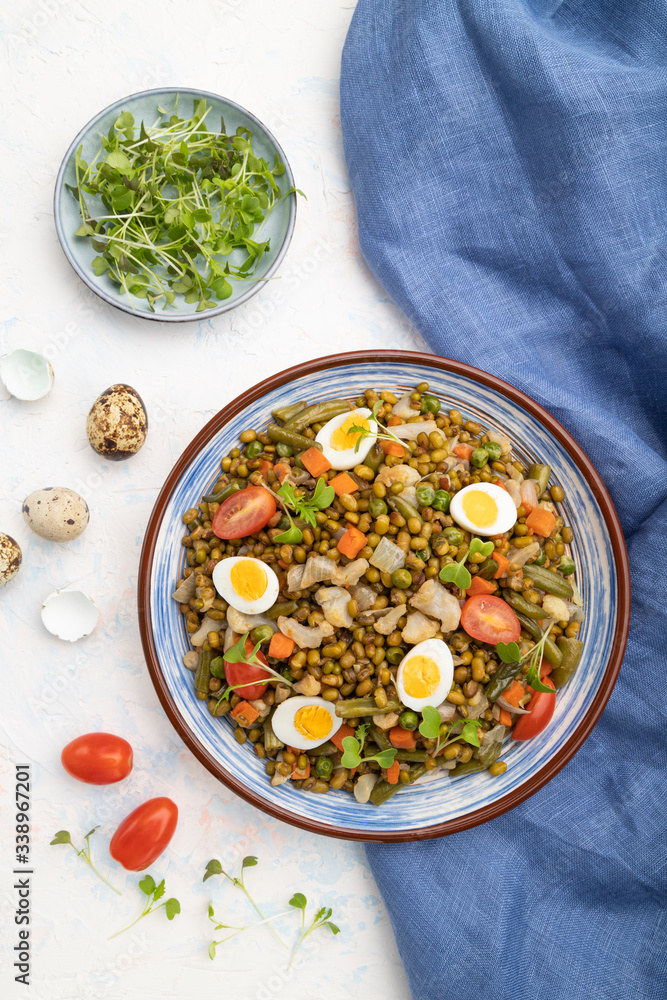 Mung bean porridge with quail eggs, tomatoes and microgreen sprouts on a white concrete background. Top view, close up. Mung bean porridge with quail eggs, tomatoes and microgreen sprouts on a white concrete background. Top view, close up.