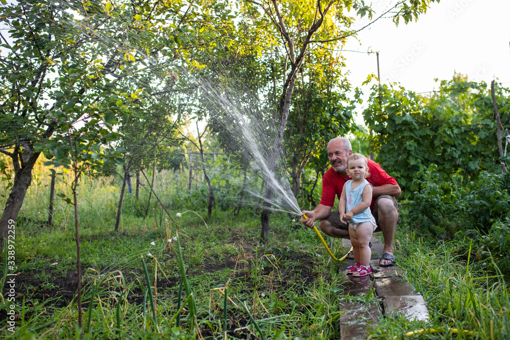 Grandfather with granddaughter in the country water the garden Grandfather with granddaughter in the country water the garden