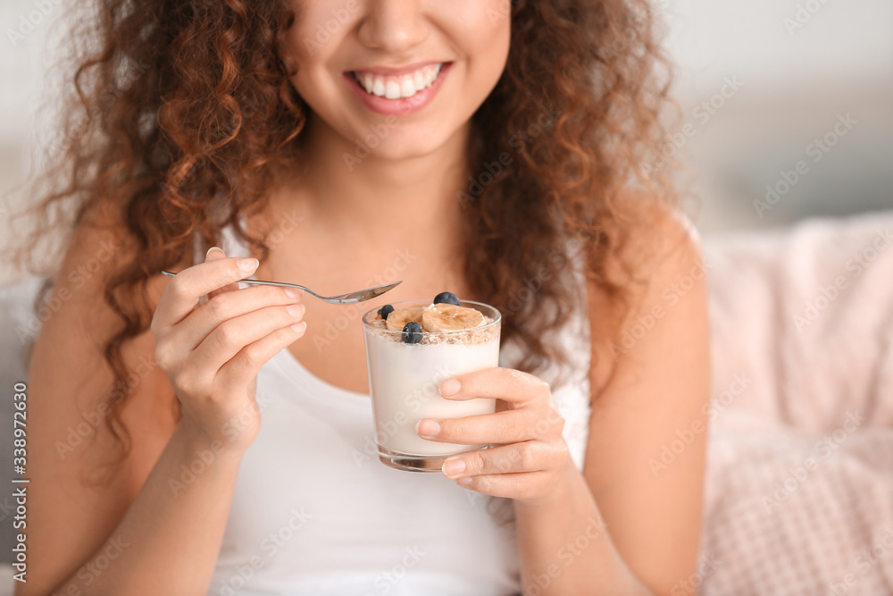 Young woman eating tasty yogurt at home, closeup Young woman eating tasty yogurt at home, closeup