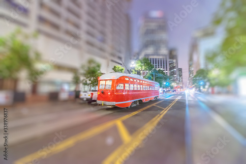 Red tram speeding up in Market Street at night, San Francisco.
