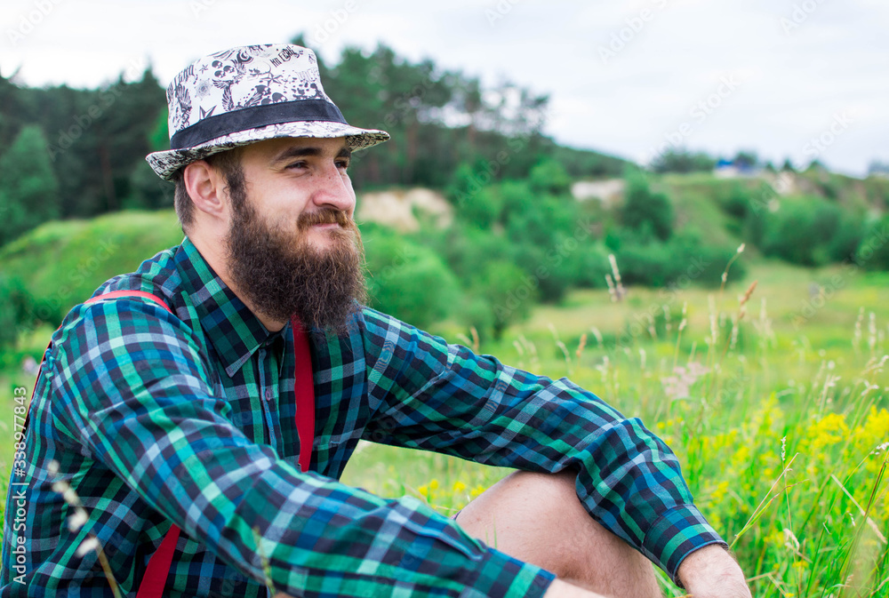 Handsome man hipster with beard on serious face in cloth shirt and suspenders sunny outdoor on mountain top against cloudy sky on natural. Tourism concept. Wonderful landscape. Handsome man hipster with beard on serious face in cloth shirt and suspenders sunny outdoor on mountain top against cloudy sky on natural. Tourism concept. Wonderful landscape.