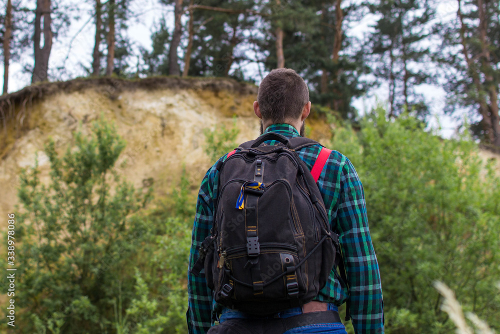 Handsome man hipster with beard on serious face in cloth shirt and suspenders sunny outdoor on mountain top against cloudy sky on natural. Tourism concept. Travel with a backpack. Wonderful landscape. Handsome man hipster with beard on serious face in cloth shirt and suspenders sunny outdoor on mountain top against cloudy sky on natural. Tourism concept. Travel with a backpack. Wonderful landscape.