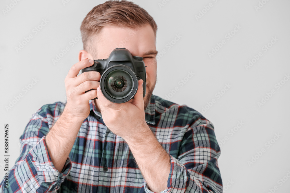 Male photographer with camera on grey background
