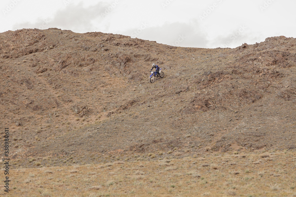 Man riding a motorbike in the steppes of Mongolia, on the hills of Mongolia