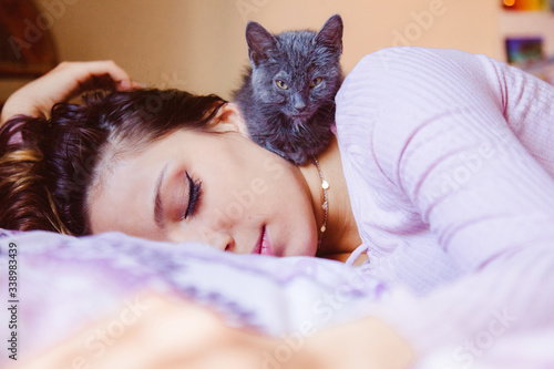 Beautiful loneliness woman taking a nap at home with her cat. Fluffy kitten sleeping with tired woman. Depression and solitude emotions for animal lovers. Indoor with pets lifestyles.