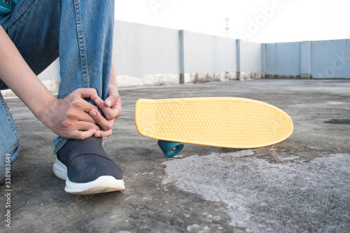 A person sitting and hold the leg that is injured in an accident. Skateboard