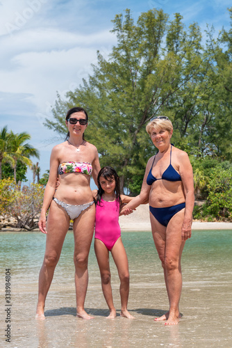 Happy family along the shoreline. Causasian woman with daughter and mother, three people smiling on the beach © jovannig