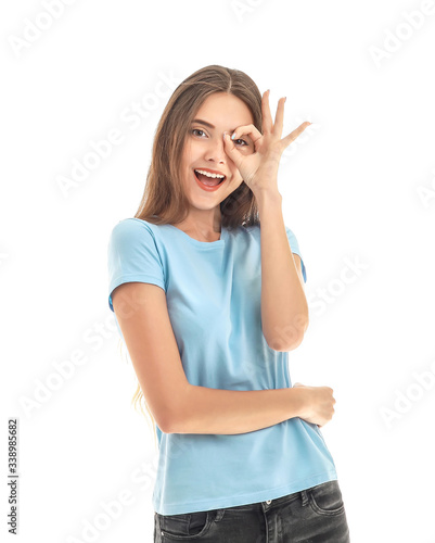 Beautiful young woman showing OK gesture on white background