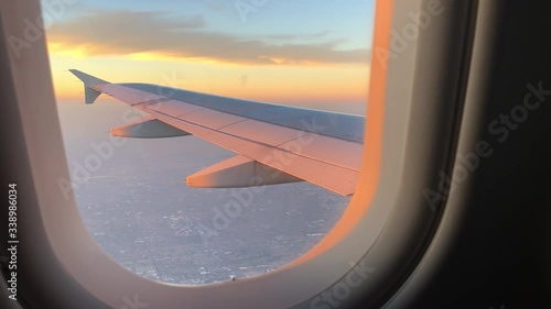 Looking out an airplane window at a magnificent and colorful sunset after taking off from the airport. Wing view from window seat.