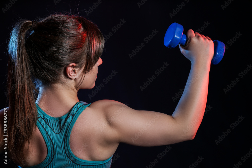 Sporty muscular woman with dumbbells on dark background